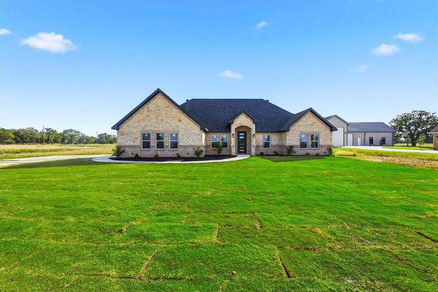 French provincial home featuring a front lawn and stone siding