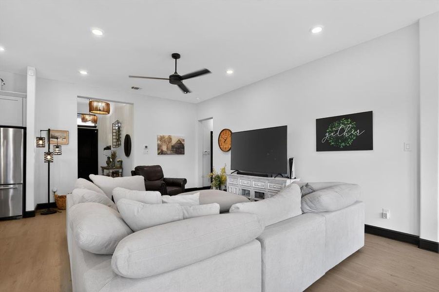 Open-concept living area featuring light wood-finish flooring, recessed lighting, and a contemporary ceiling fan
