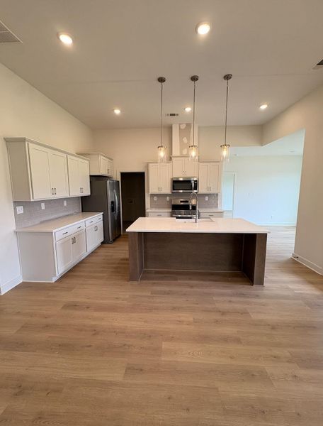 Spacious kitchen featuring an expansive central island with three pendant lights