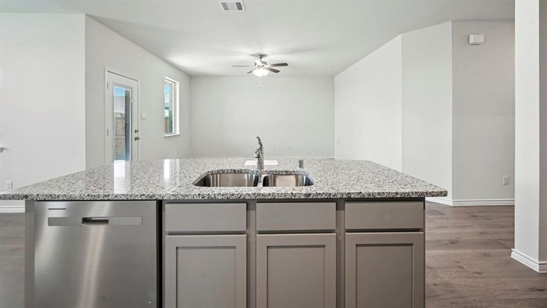 Kitchen island featuring a double basin stainless steel sink, pull-down faucet, and integrated dishwasher