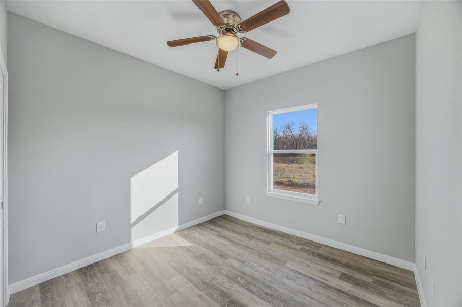 Well-lit room features a modern ceiling fan and durable wood-look flooring.