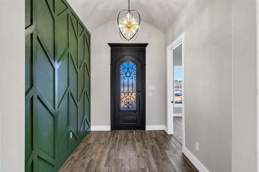 Entryway featuring lofted ceiling, wood-type flooring, and a notable chandelier