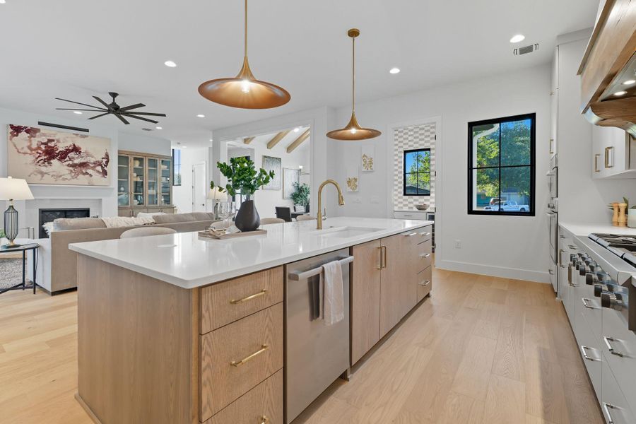 Kitchen featuring decorative light fixtures, a fireplace, light wood-style flooring, stainless steel appliances, and recessed lighting