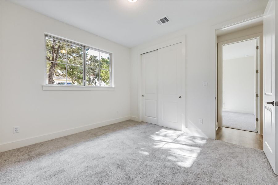 Unfurnished bedroom featuring light carpet and a closet Unfurnished bedroom featuring light carpet and a closet