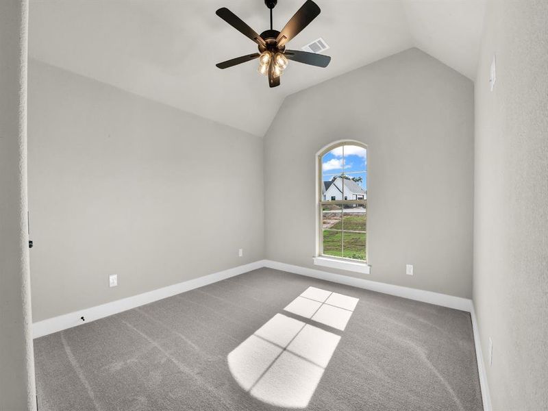 Carpeted empty room featuring vaulted ceiling and a ceiling fan Carpeted empty room featuring vaulted ceiling and a ceiling fan