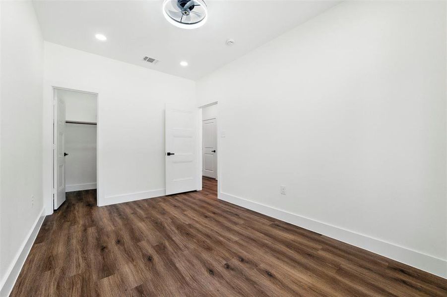 Unfurnished bedroom featuring dark wood-type flooring, a spacious closet, and recessed lighting
