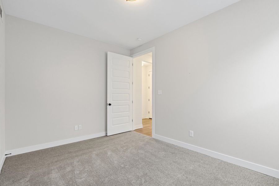 Plush carpeting, neutral wall tones, and a modern paneled interior door Plush carpeting, neutral wall tones, and a modern paneled interior door