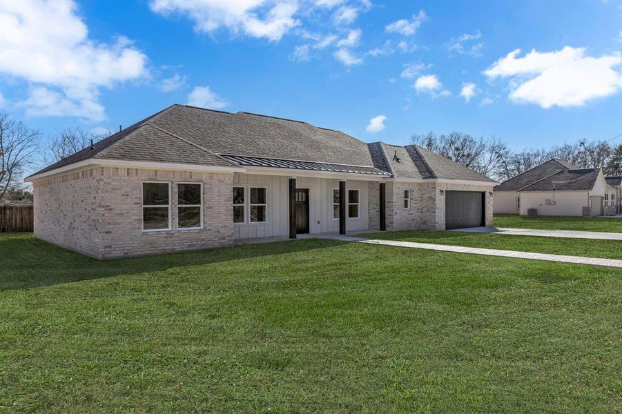 View of front of property with a garage and a front lawn