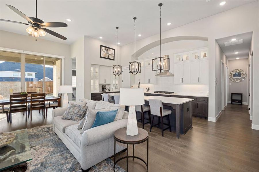 Living room with ceiling fan with notable chandelier and dark hardwood / wood-style floors
