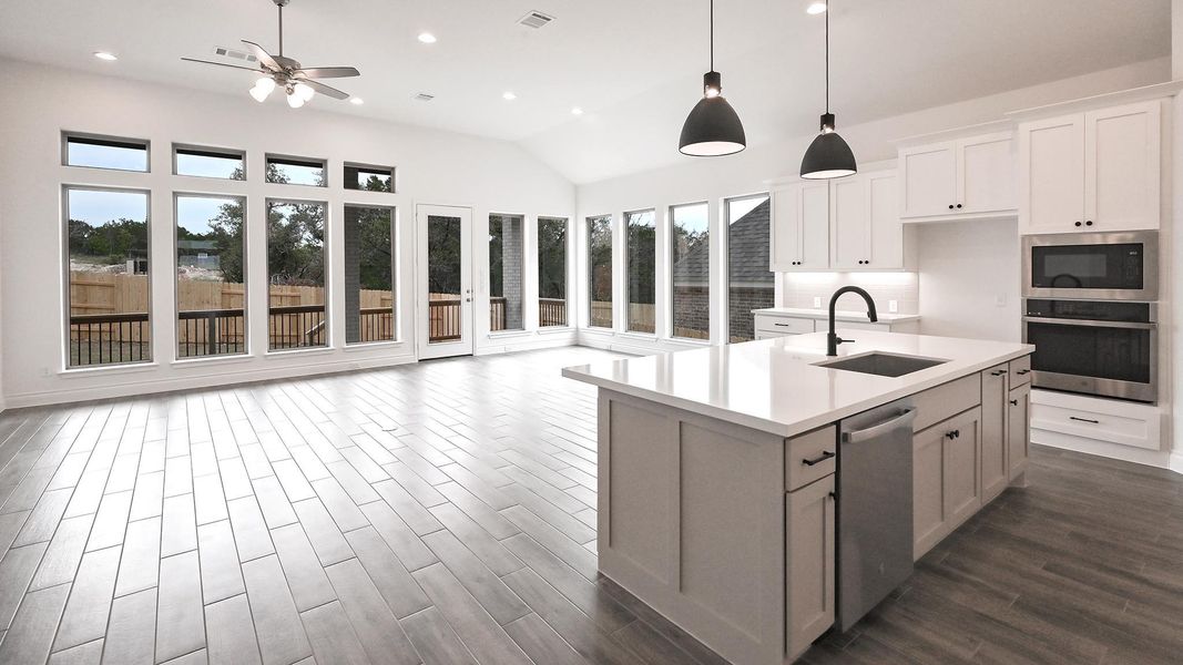 Kitchen with stainless steel appliances, a sink, a ceiling fan, light countertops, and dark wood-style floors Kitchen with stainless steel appliances, a sink, a ceiling fan, light countertops, and dark wood-style floors