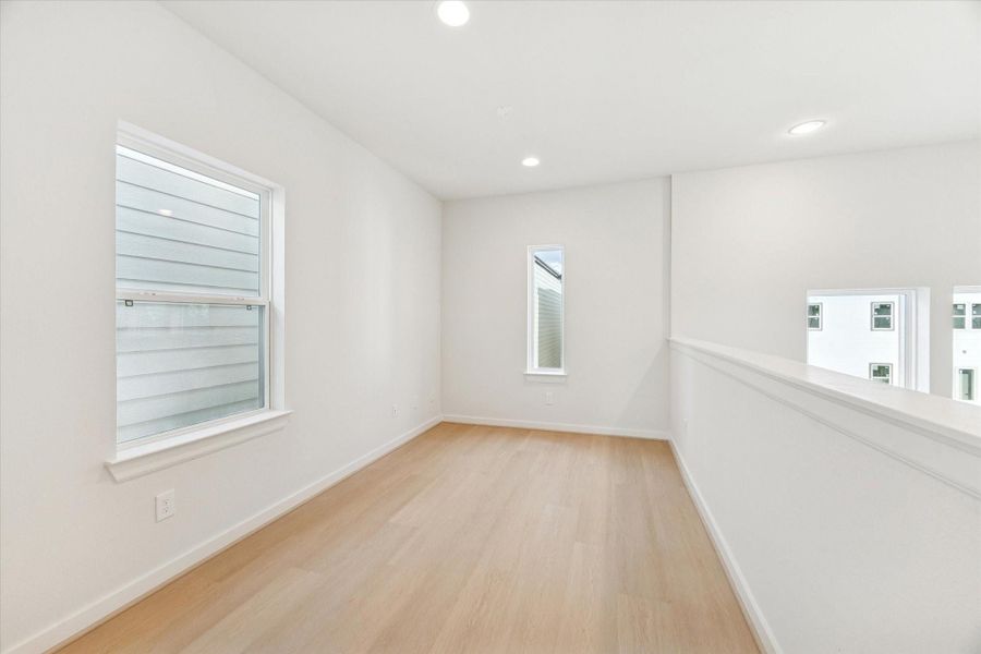 Third-floor study features bright windows with plenty of natural light and a view from the railing down into the living room, adding connection and openness to the space.