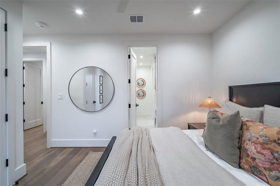 Bedroom with ensuite bathroom, ceiling fan, and light hardwood / wood-style flooring