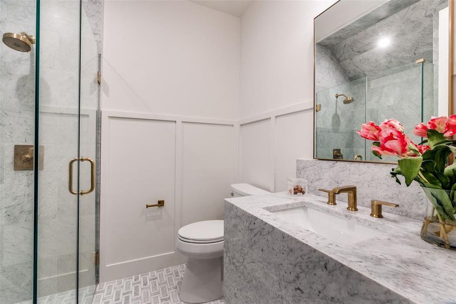 Full bathroom with a stall shower, toilet, vanity, a decorative wall, and a wainscoted wall Full bathroom with a stall shower, toilet, vanity, a decorative wall, and a wainscoted wall