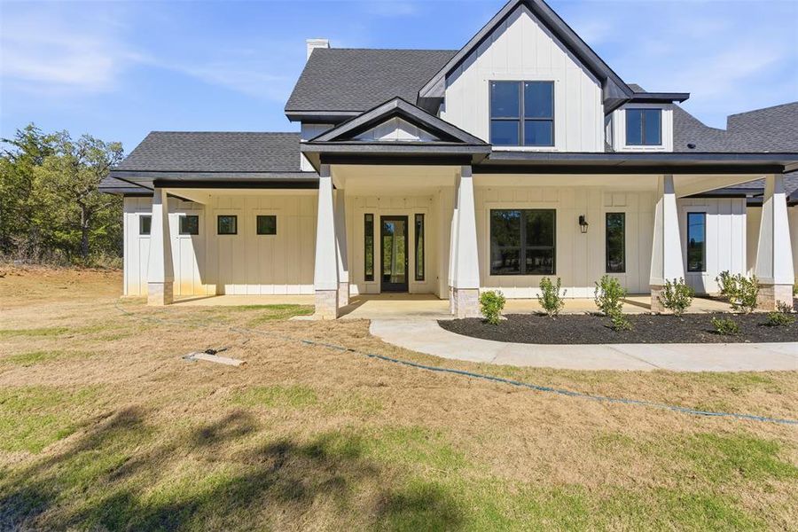 Modern inspired farmhouse with roof with shingles, board and batten siding, a porch, and a front yard Modern inspired farmhouse with roof with shingles, board and batten siding, a porch, and a front yard