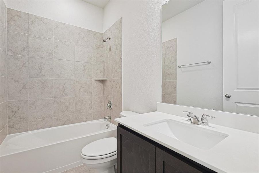 Bathroom featuring bathtub / shower combination, vanity, and a textured wall Bathroom featuring bathtub / shower combination, vanity, and a textured wall