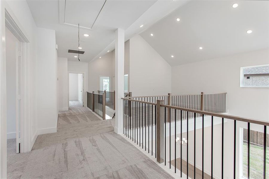 Corridor featuring lofted ceiling and light carpet