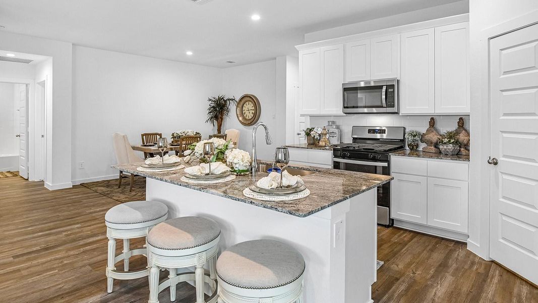 Bright and spacious kitchen with granite countertops, stainless steel appliances, and an island with bar seating.