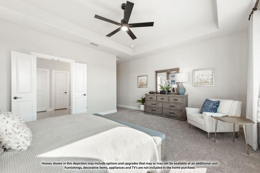 Spacious bedroom with tray ceiling, ceiling fan, carpet, dresser, and double doors leading to closet and bathroom. Spacious bedroom with tray ceiling, ceiling fan, carpet, dresser, and double doors leading to closet and bathroom.