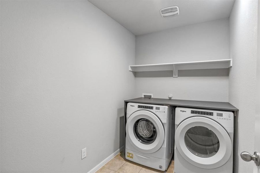 Clothes washing area featuring washer and clothes dryer and light tile patterned flooring