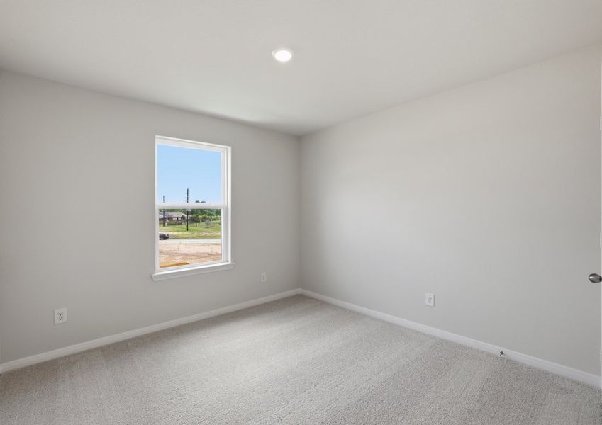 Carpeted secondary bedroom featuring a window with a backyard view.