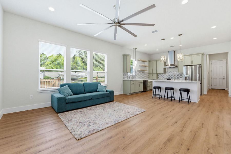 A well-lit, open-concept living area boasts light wood flooring and a contemporary kitchen.