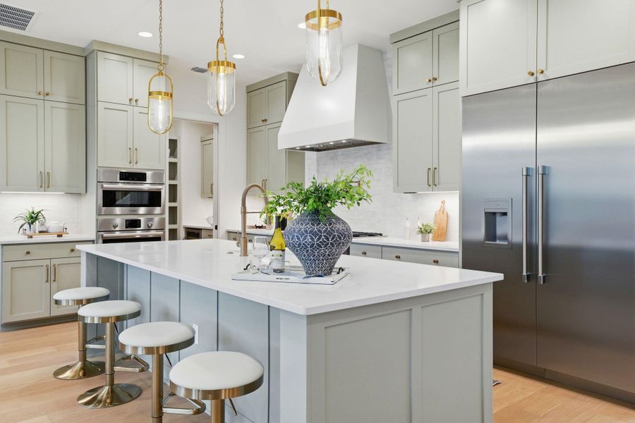 Kitchen featuring gray cabinetry, stainless steel appliances, light wood-type flooring, pendant lighting, and an island with sink