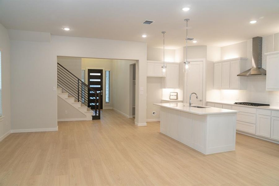 Open-concept living space featuring wood-finish flooring, recessed lighting, and a modern kitchen Open-concept living space featuring wood-finish flooring, recessed lighting, and a modern kitchen