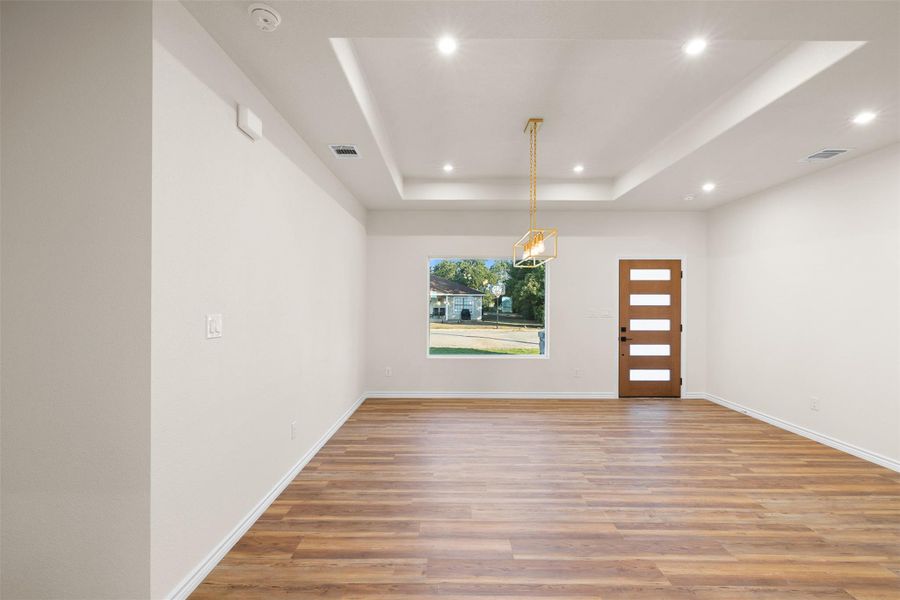 Foyer with a raised ceiling, light wood-style floors, and recessed lighting Foyer with a raised ceiling, light wood-style floors, and recessed lighting