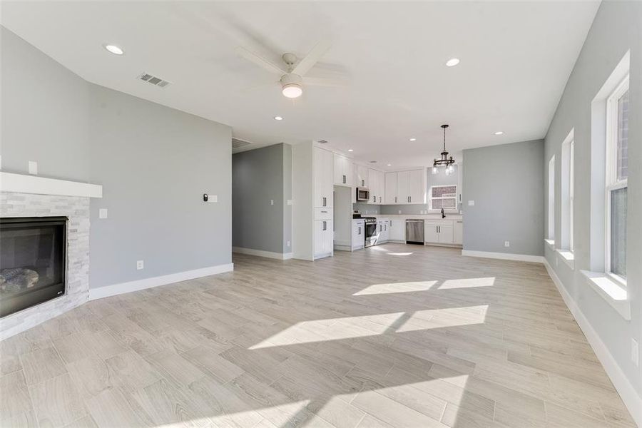 Unfurnished living room featuring sink, ceiling fan with notable chandelier, and a fireplace