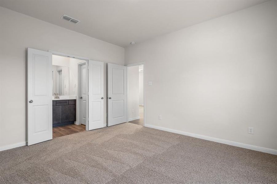 Unfurnished bedroom with dark colored carpet and ensuite bathroom