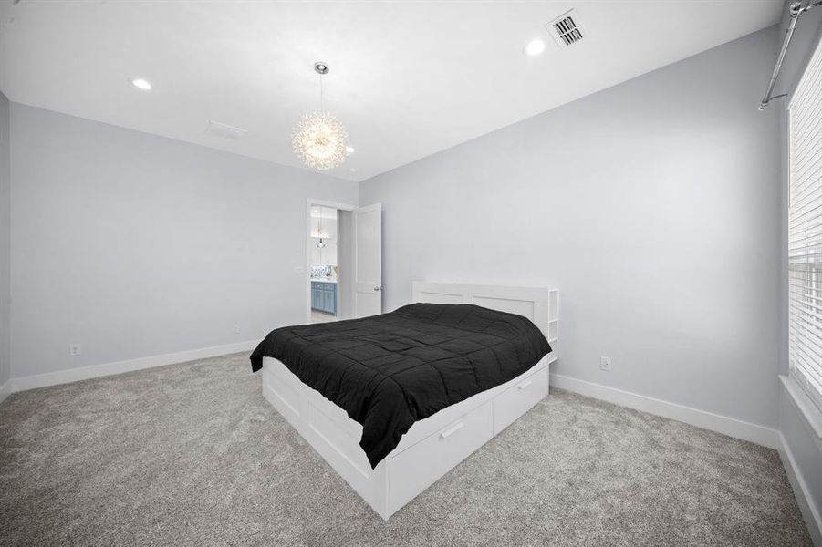 Bedroom featuring light colored carpet and hanging lights