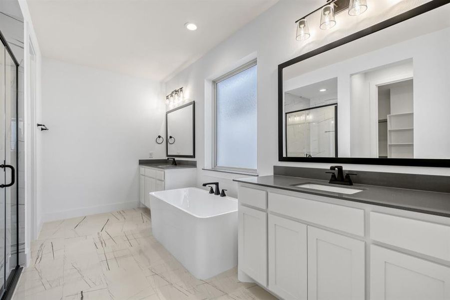 Bathroom featuring a soaking tub, two vanities, a marble finish shower, recessed lighting, and light marble finish flooring