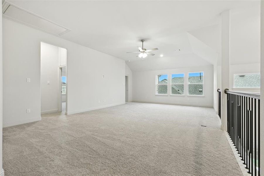 Spare room featuring light colored carpet, a ceiling fan, attic access, and lofted ceiling
