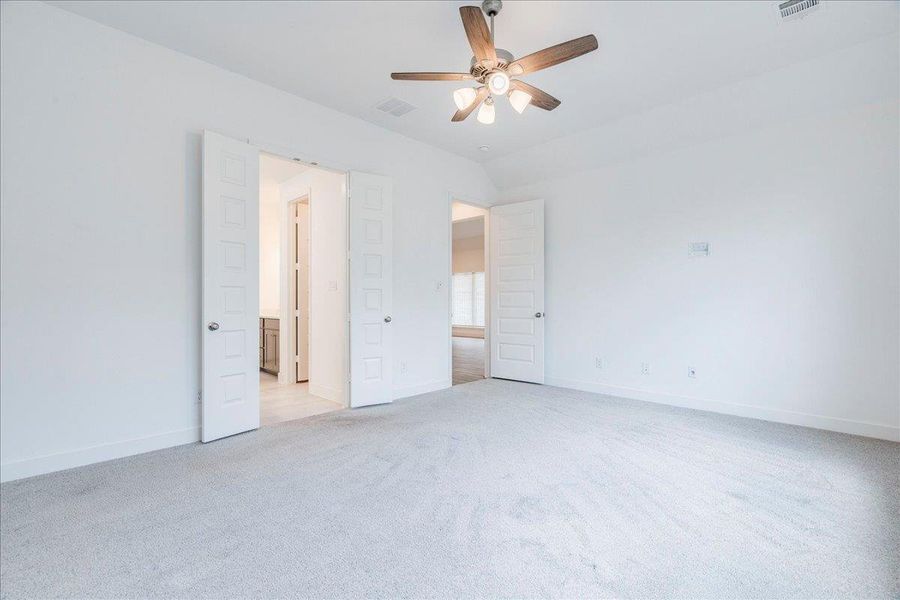Spacious room featuring light-colored carpeting, a ceiling fan with integrated lighting, and white walls