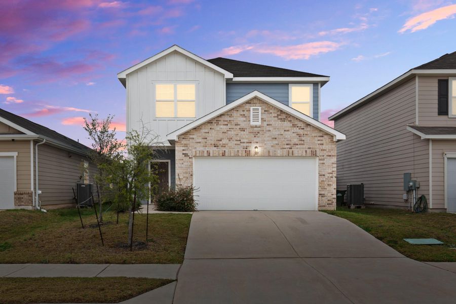 Traditional home with brick siding, driveway, board and batten siding, and a lawn