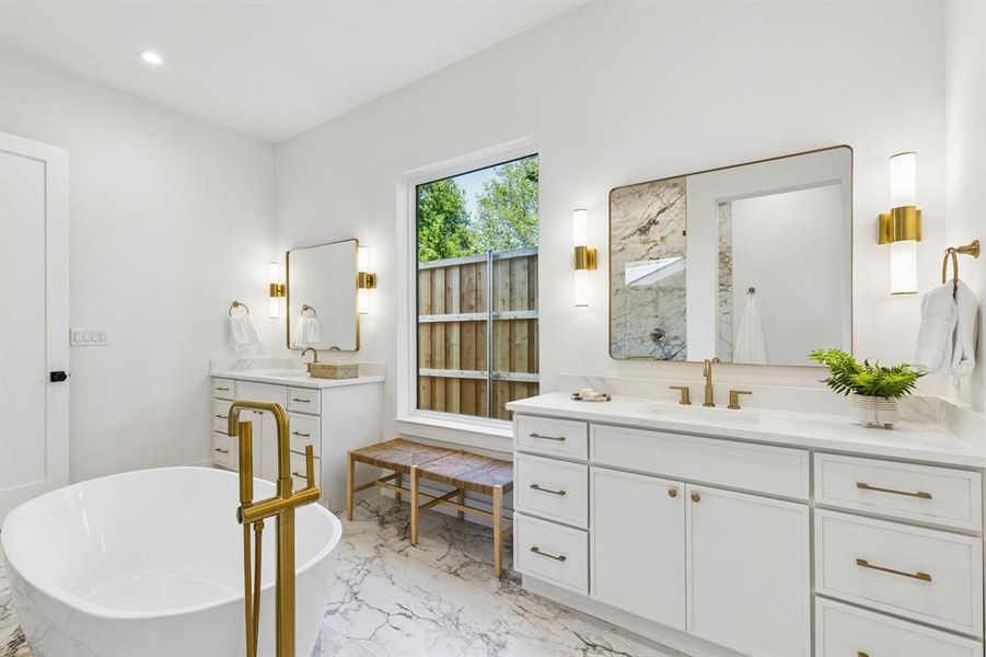 Full bath with two vanities, a soaking tub, light marble finish flooring, and recessed lighting