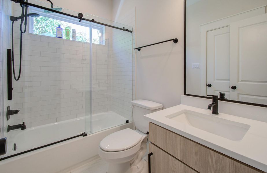 Your guests will enjoy the perfect blend of form and function in this elevated bath. The combination tub and shower is outfitted with high-end rainforest fixtures and encased in a modern glass enclosure with custom sliding doors and designer hardware. Thoughtful lighting and premium finishes complete this inviting, spa-quality space.