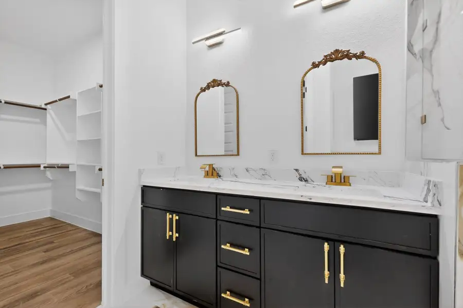 Double vanities with rich cabinetry complement the adjoining walk-in closet with ample storage solutions.