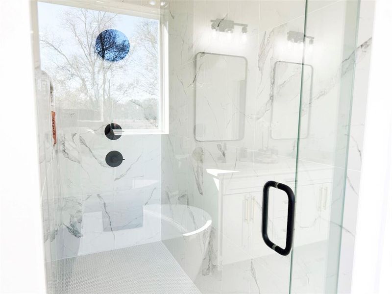 Full bath with a marble finish shower