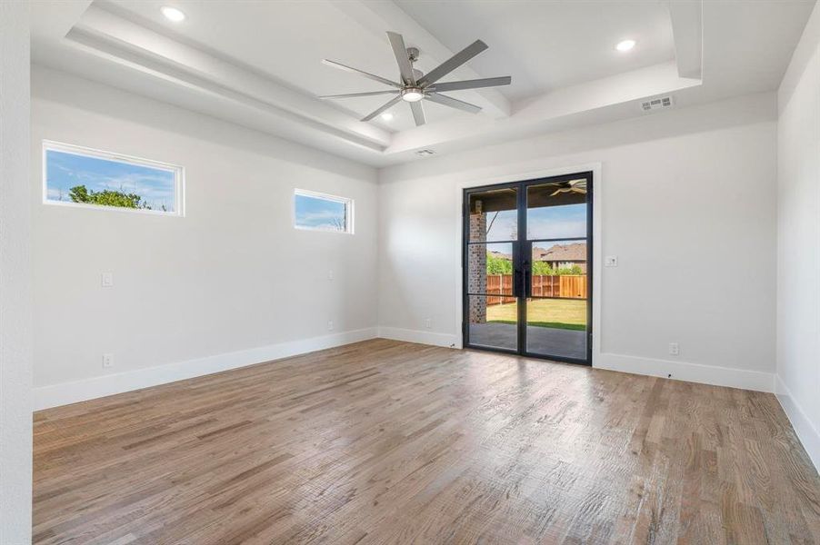 Unfurnished room with a tray ceiling, ceiling fan, hardwood / wood-style floors, and french doors