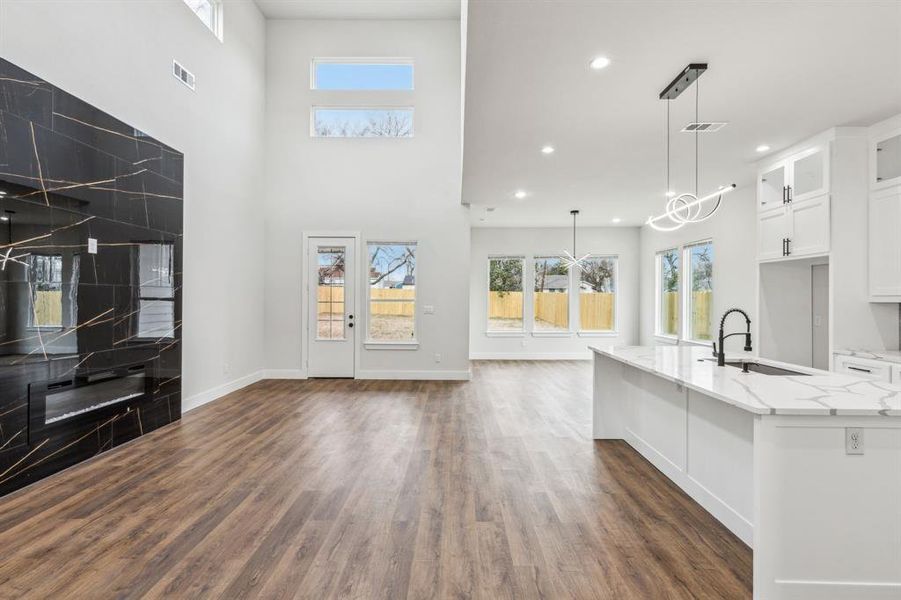 Kitchen with white cabinetry, light stone counters, hanging light fixtures, and sink