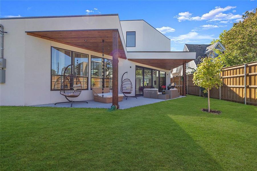 Rear view of property with an outdoor living space, a lawn, and a patio