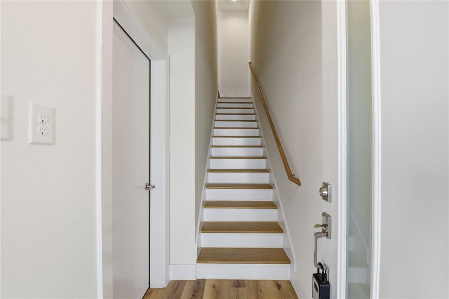 Entryway with a straight staircase featuring wood steps and white risers.