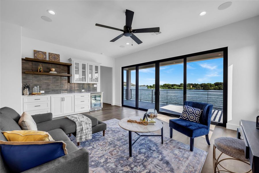 Living room with recessed lighting, bar with sink, a water view, dark wood-style flooring, and wine cooler