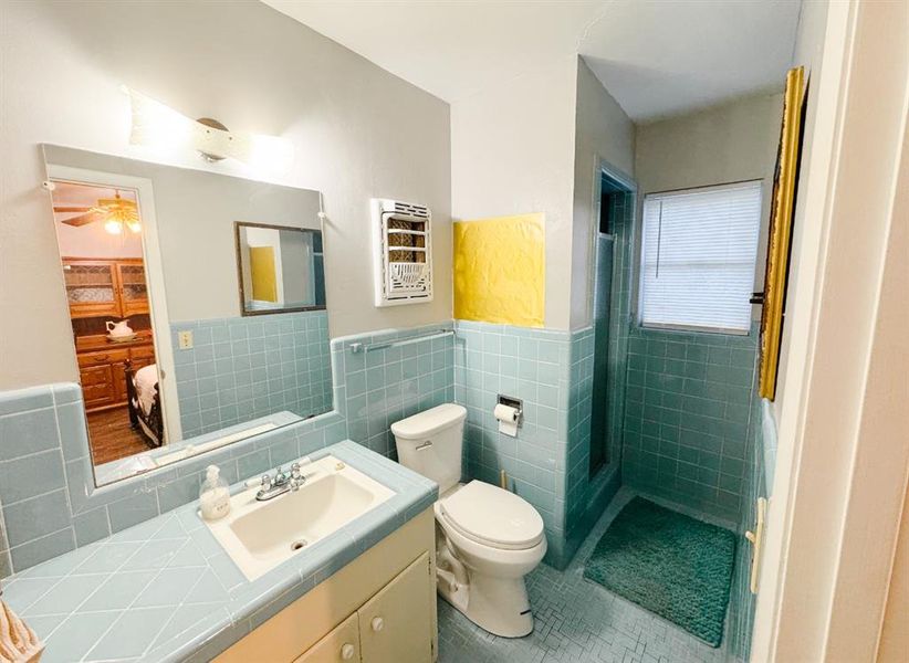 Full bath with tile walls, vanity, a shower stall, tile patterned flooring, and a wainscoted wall