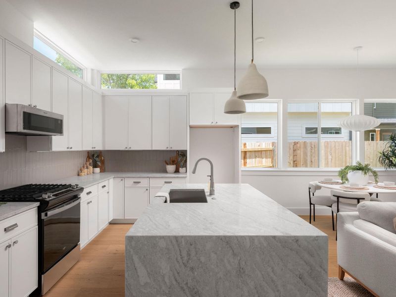 A well-lit culinary space featuring an island, integrated appliances, and a seamless flow to the adjacent dining area.