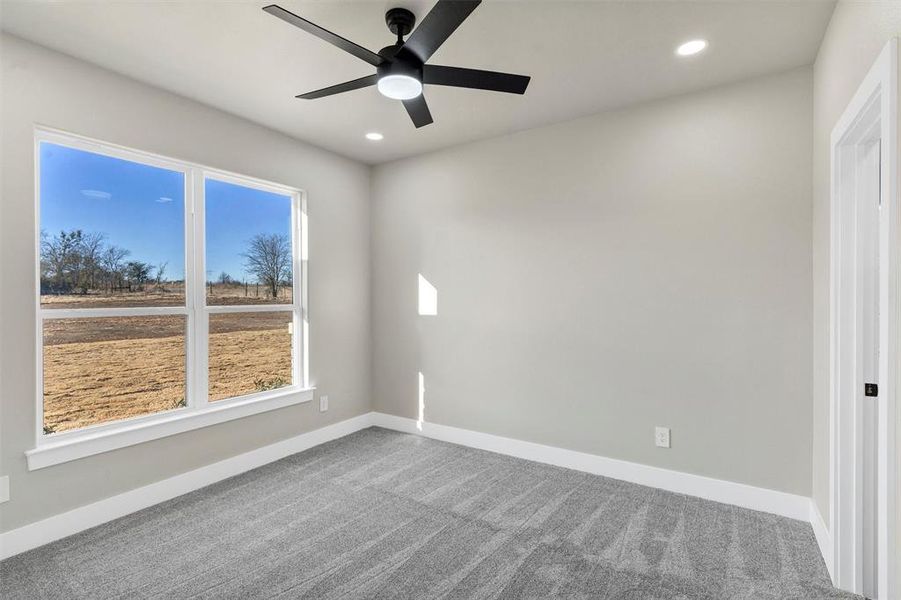 Carpeted empty room with a healthy amount of sunlight and ceiling fan