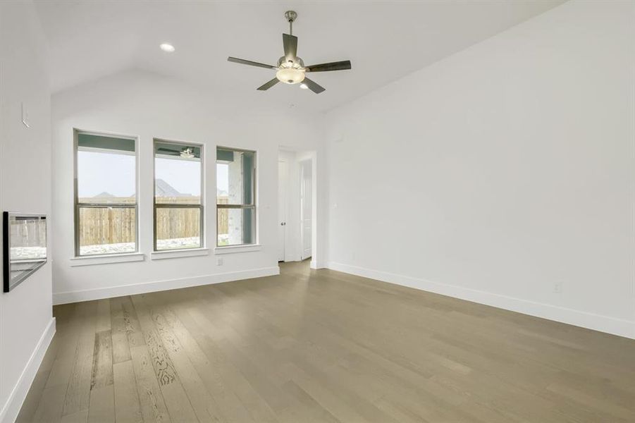 Bright interior space featuring a vaulted ceiling with a ceiling fan, recessed lighting, wood-finish flooring, and a series of three windows