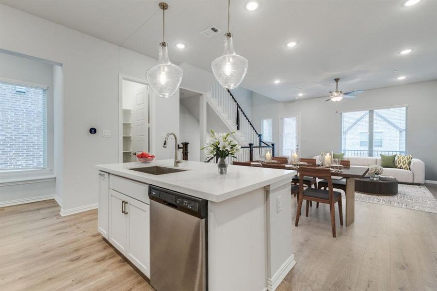 Kitchen with a sink, light wood-type flooring, open floor plan, and stainless steel dishwasher