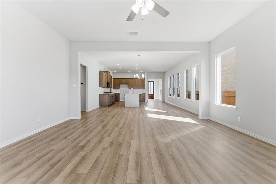 Unfurnished living room featuring light wood-style flooring, a chandelier, a ceiling fan, and recessed lighting